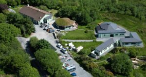 Aerial image of Common Knowledge Centre with cars in a carpark and small buildings in a woody wetland area