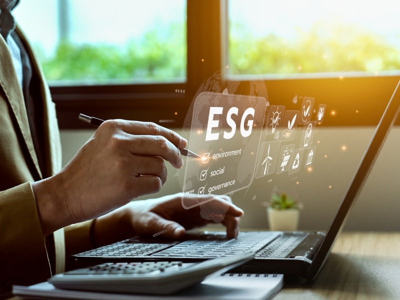 A person sat at a laptop with the words ESG highlighted for Environmental, Social and Governance