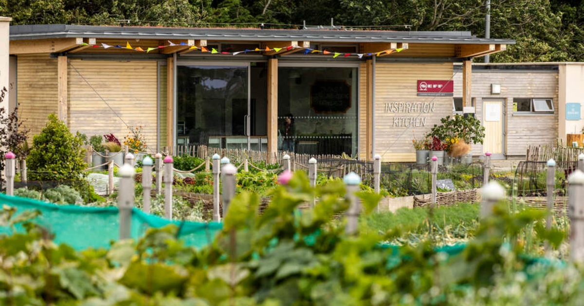 Image of urban farm and vegetable patch with wooden cabin in the background with the words Inspiration Kitchen.