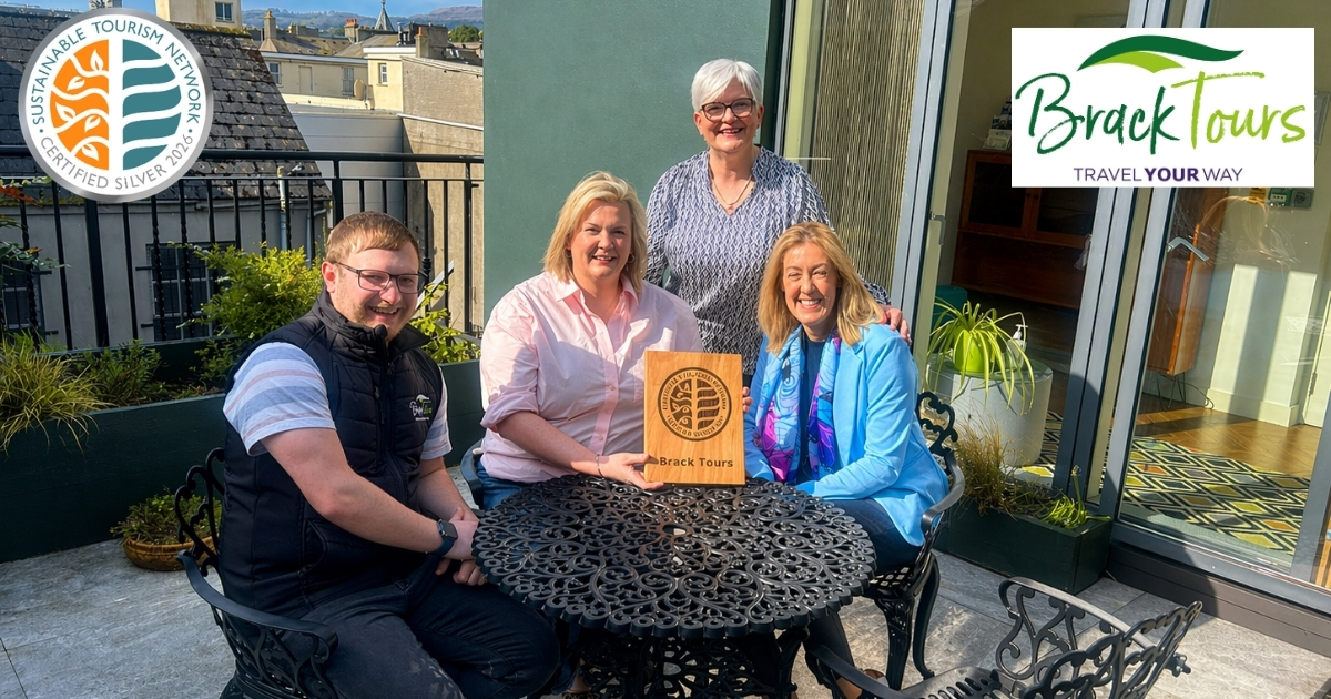 Sustainable Tourism Network logo. Brack Tours logo. Image of four people sitting at a garden table in the sun smiling with their wooden sustainable tourism certification plaque.